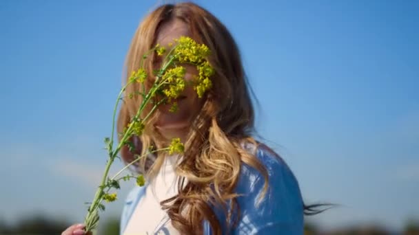 Lekfull tjej som visar våldtäktsgren. Leende kvinna leker med blomman utomhus. — Stockvideo