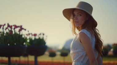 Sensual woman looking at camera outdoors. Beautiful girl turning face to sun. 