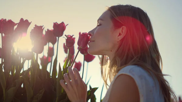 Closeup female touching flower bud. Smiling girl enjoying tulip in sun beams. — Stok fotoğraf