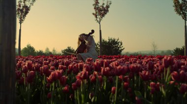 Flower garden with unknown young woman with cello in morning.