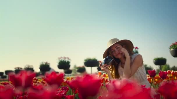 Bonita mujer coqueteando entre flores rojas. Mujer feliz enamorada sentada en el jardín. — Vídeos de Stock