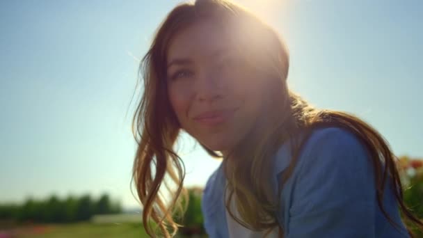 Портрет счастливой женщины, улыбающейся летом на цветочном фоне в мягком закате — стоковое видео