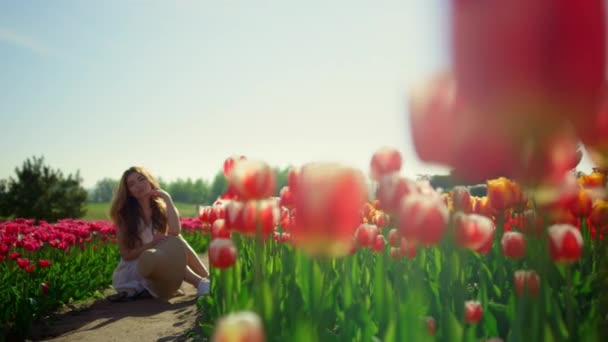 Spring flower garden in bloom with unrecognizable girl sitting on road — Vídeo de stock