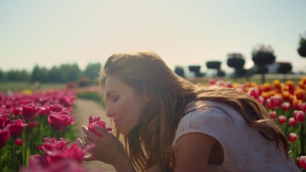 Emocjonalna dziewczyna pachnąca kwiatami w świetle zachodu słońca. Piękna kobieta cieszy się kwiatem — Wideo stockowe