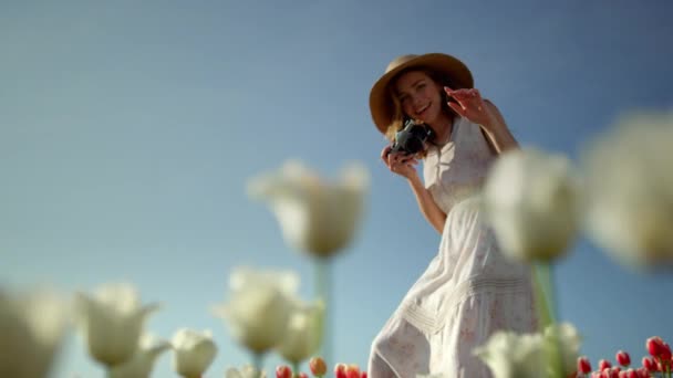 Menina bonita com fotocâmera rindo no campo de tulipas. Mulher tirando fotos. — Vídeo de Stock