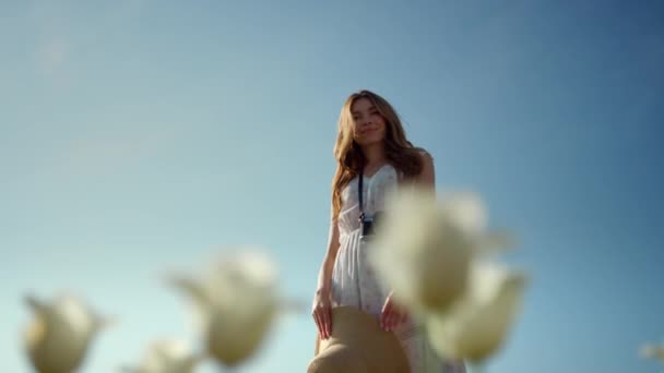 Camera rotation around young woman enjoying white flowers on blue sky background — Vídeo de stock