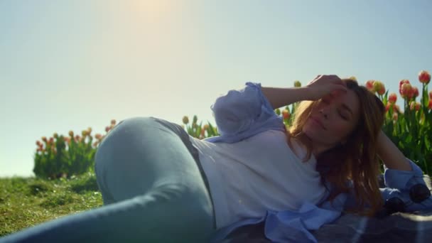 Nyugodt nő fekszik a tulipánkertben. Mosolygó hölgy játszik hajat lágy napsütésben. — Stock videók