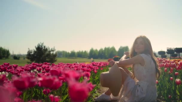 Chica juguetona coqueteando entre flores al atardecer. Mujer relajada disfrutando de la primavera — Vídeos de Stock