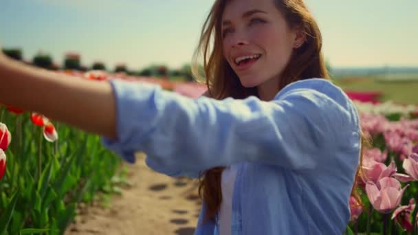 Mladá žena dělá selfie v krásné květinové zahradě. Dívka se usmívá v chytrém telefonu — Stock video