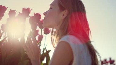 Closeup female touching flower bud. Smiling girl enjoying tulip in sun beams.