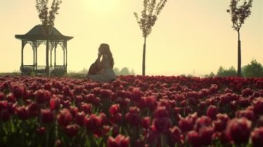 Unknown woman playing cello in blooming garden in springtime. Girl performance