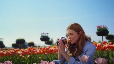 Emotional woman looking at blooming garden. Happy girl taking photo of flowers.
