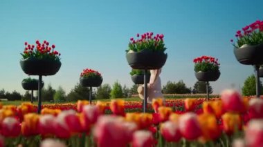 Kimliği belirsiz bir kadın, güzel bir bahçede ağır çekimde hızlı hareket ediyor..