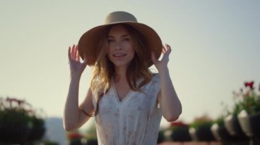Attractive girl taking off sunhat in sunny day. Young lady enjoying springtime.