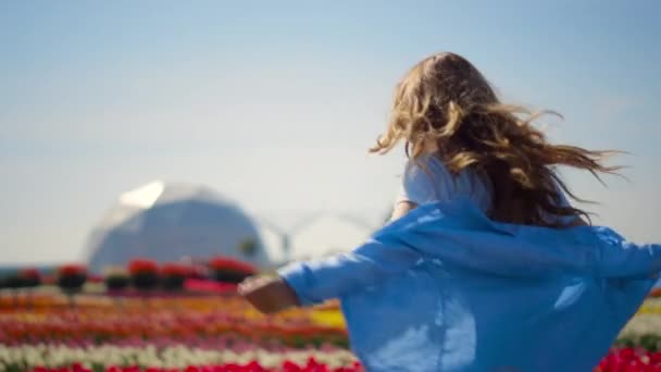 Mooi meisje dansend in bloementuin. Jongedame voelt vreugde in het voorjaarspark. — Stockvideo