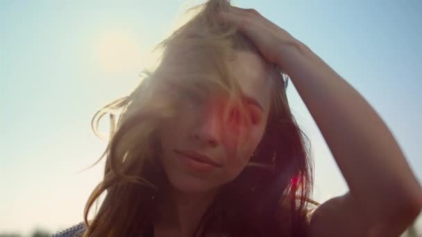 Porträt einer Frau, die im Licht direkt in die Kamera blickt. Lächelndes Mädchen spielt Haare — Stockvideo