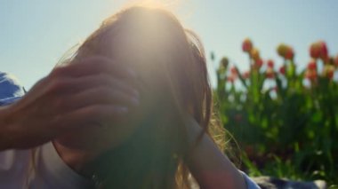 Romantic blue-eyed woman relaxing in soft sunlight in tulip field background.