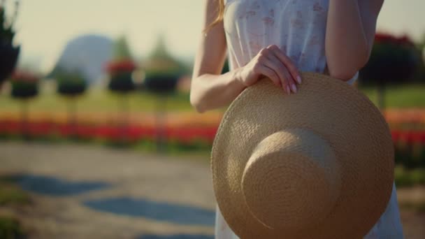 Nahaufnahme schöne Frau hält Damen Sonnenhut in den Händen im Sommer Garten im Freien. — Stockvideo