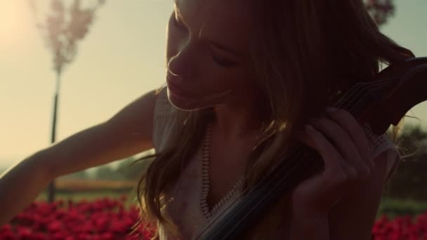 Close-up geïnspireerd jonge vrouw spelen cello in bloei zomer tuin buiten. — Stockvideo