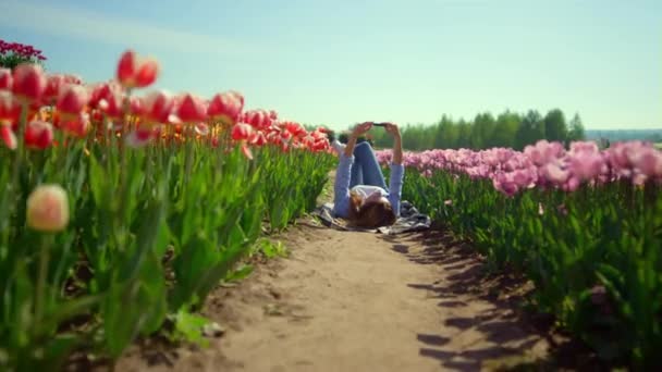 Hezká dívka drží mobilní telefon v ruce v květinové zahradě ve slunečný den. — Stock video