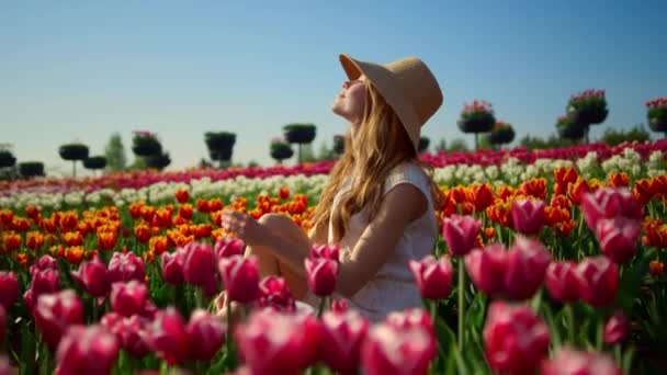 Красивая женщина наслаждается солнцем на тюльпановом поле. Расслабленная девушка поворачивается лицом к солнцу. — стоковое видео