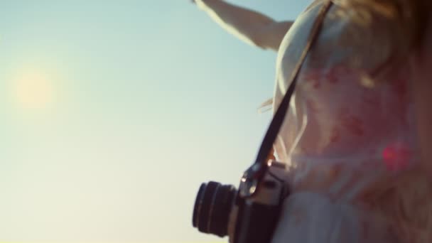 Jonge vrouw met camera kijken bij de hand op zonneschijn achtergrond outdoor. — Stockvideo