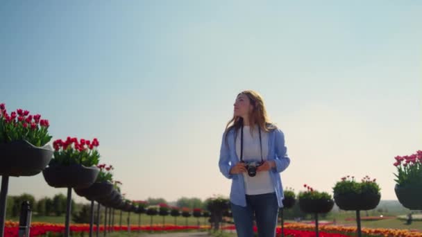 Glad kvinnlig fotograf körs i slow motion i blommande park i solig dag. — Stockvideo