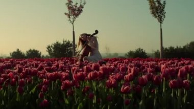 Flower garden with unknown young woman with cello in morning.