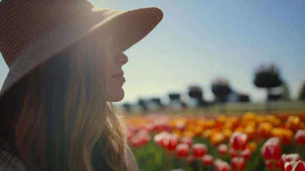 Model posing in spring flower field in bright sunshine. Woman profile in sunhat. — Stok fotoğraf