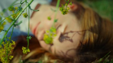Portrait of unrecognizable woman with wild flower enjoying sun with closed eyes.