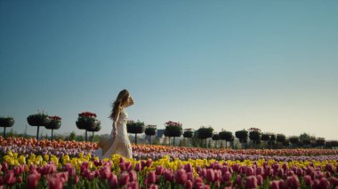 Çiçek bahçesinde dinlenen genç bir kadın. Kız kendini dışarıda özgür hissediyor 