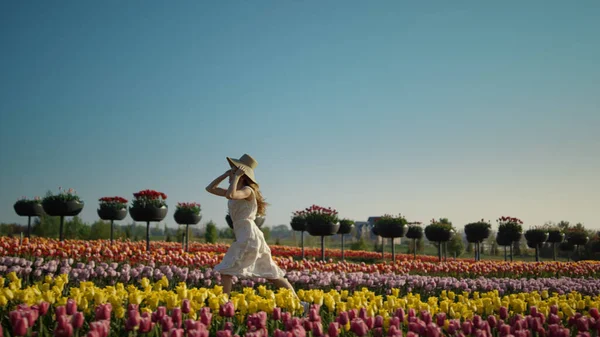 Młoda kobieta biegająca na polu tulipanów. Dziewczyna porusza się szybko w ogrodzie kwiat. — Zdjęcie stockowe