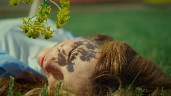 Fille détendue posant avec des fleurs sauvages dans le parc vert. Branche ombre sur joli visage — Photo