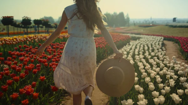 Unrecognizable girl running in tulip field. Young woman legs running in park. — Stock Photo, Image