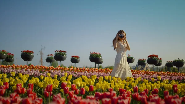 Девушка с камерой делает фото красивых тюльпанов. Девушка гуляет в парке. — стоковое фото