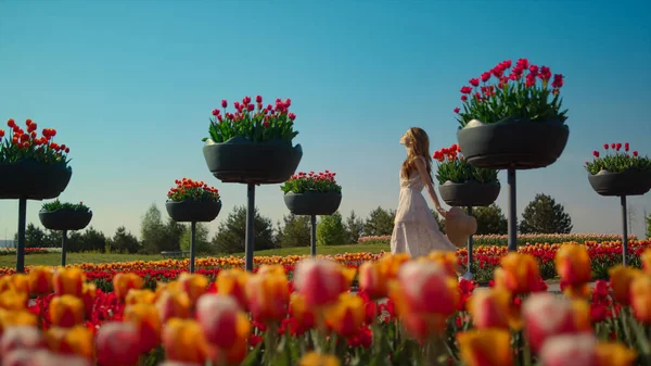 Nieznana kobieta w sukience spaceru przez jasny letni ogród w kwitnących kwiatów — Zdjęcie stockowe