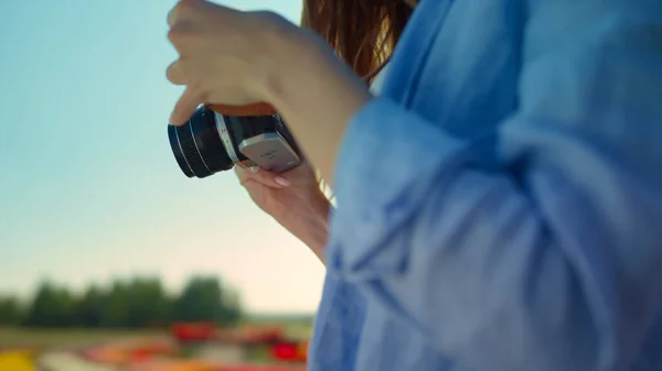 Zbliżenie kobieta ręce gospodarstwa profesjonalny aparat fotograficzny w kwitnący ogród odkryty — Zdjęcie stockowe