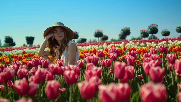 Zrelaksowana kobieta siedząca w pięknym wiosennym ogrodzie. Widok kwitnącego pola tulipanowego. — Zdjęcie stockowe