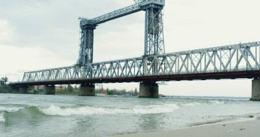 Hava manzaralı nehir köprüsü kıyısı bulutlu bir havada. Dalgalar sahili vuruyor..