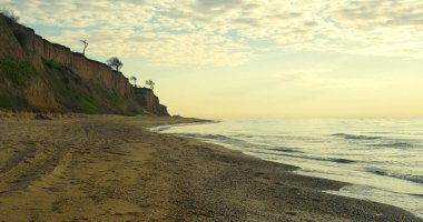 Gün batımı ufkunda deniz sahili görüntüsü. Dalgalar güzel doğa adasına çarpar..