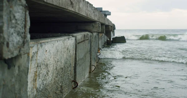 Ondas batendo ponte urbana na costa do mar em tempo nublado. Conceito de tristeza. — Fotografia de Stock