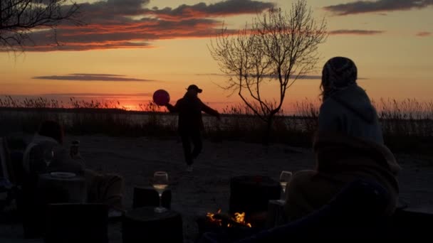 海の海岸線で楽しいビーチパーティーをしている友人グループ日没の地平線の風景. — ストック動画