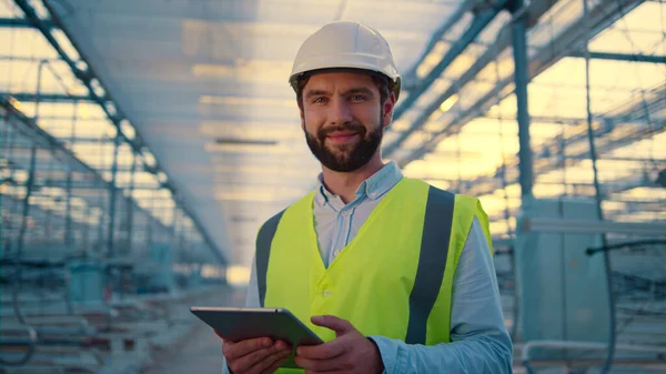 Happy engineer with tablet collecting production data analysing efficiency