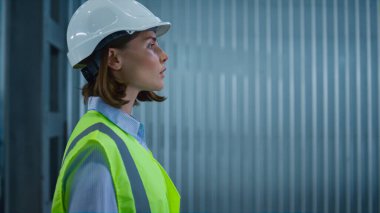 Portre depolama çalışanı imalat tesisinde yürüyor, stokları yönetiyor.