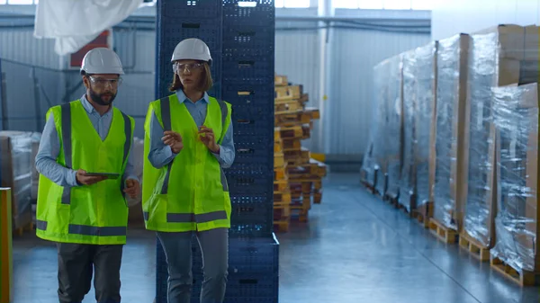 Dois trabalhadores de armazém uniformizados discutindo inspeção de produção de fabricação — Fotografia de Stock