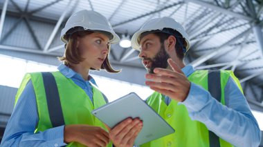 Denetçiler tableti kontrol ediyor. Üretim bilgisi analizini tartışıyorlar.