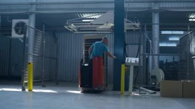 Depo kamyonu işleten adam üretim kutularını taşıyor. Depo teslimatını yönetiyor.