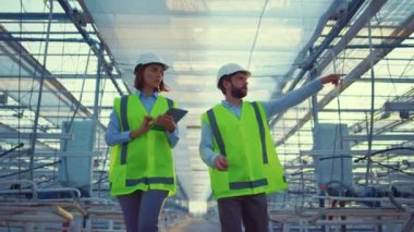 İki depo çalışanı seradaki üretim hazırlıklarını inceliyor.