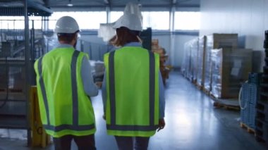 Lojistik fabrikası kompleksini araştıran iki depo işçisi üretimi tartışıyor