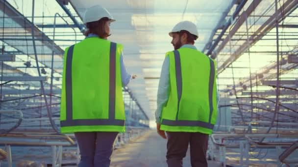 Trabajadores de manufactura vacíos caminando entre dispositivos de invernadero con uniforme verde — Vídeos de Stock